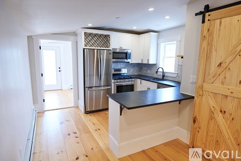 A kitchen with wooden floors and a black countertop.