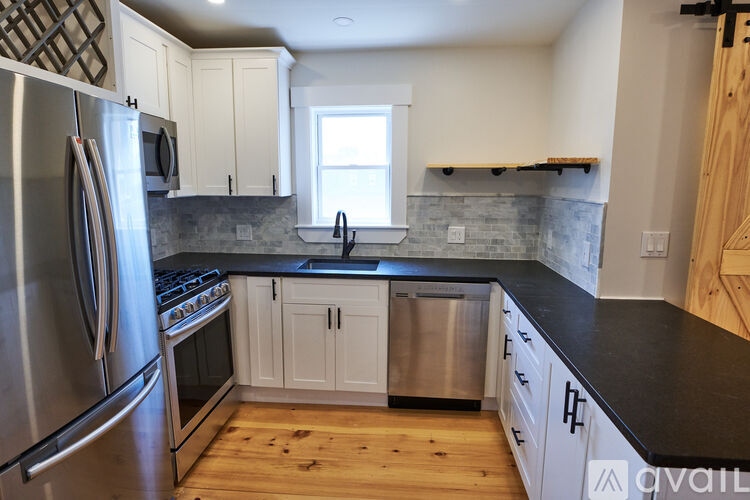 A kitchen with stainless steel appliances and wooden floors.