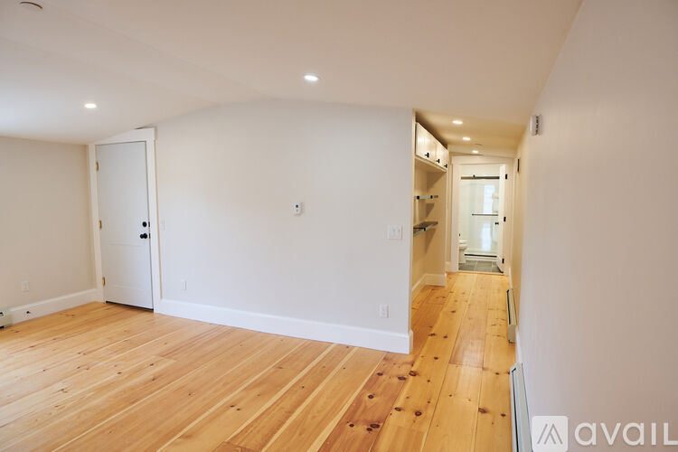 A long hallway with wood floors and white walls.