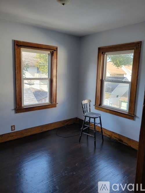 A room with a chair and two windows.