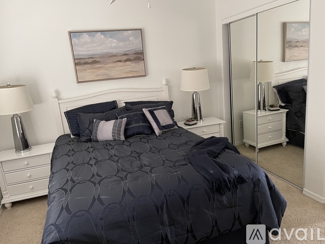 A bedroom with a large bed and a painting on the wall.