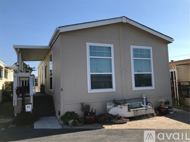 A beige house with a white door and windows is for sale.