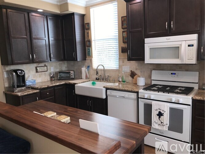 A kitchen with a white oven and microwave, brown countertop, and brown cabinets.