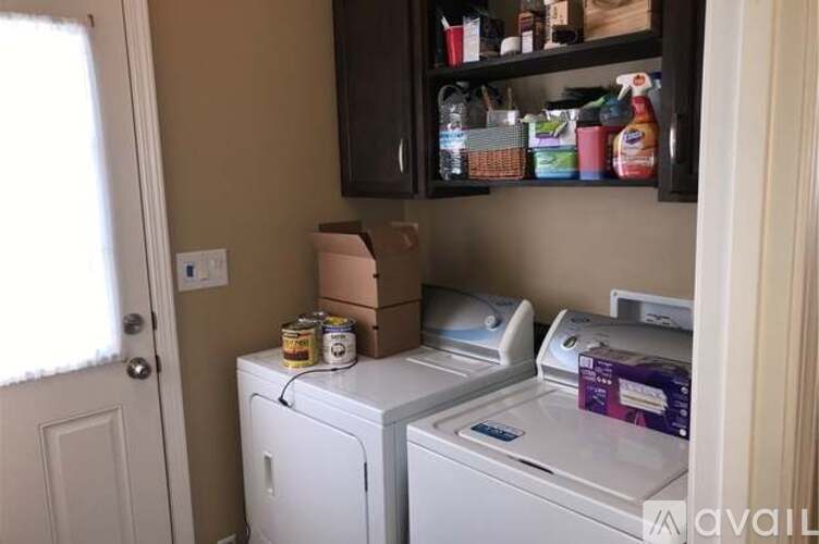 A small laundry room with a washer and dryer, a cabinet with cleaning supplies, and a door.