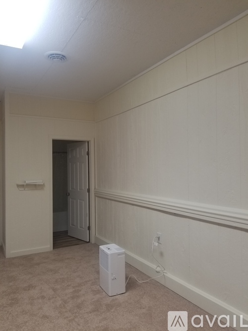 A room with a white wall and a white box on the floor.