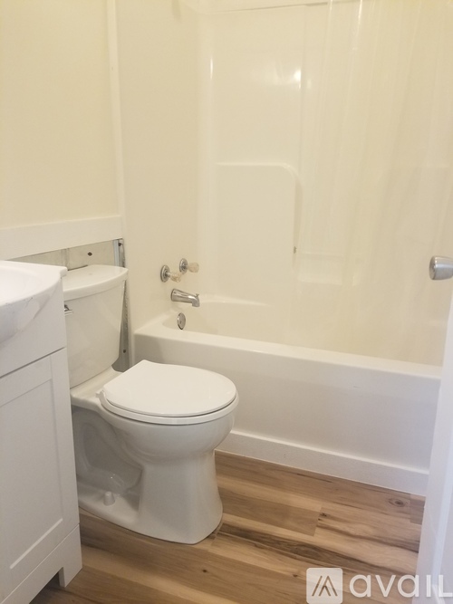 A white toilet sits in a bathroom next to a bathtub.