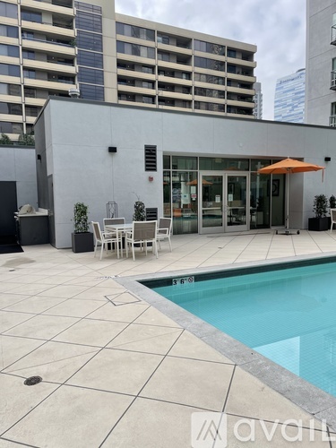 A pool with a tiled floor and a building in the background.