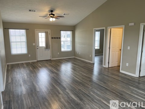 A spacious room with wood flooring and a ceiling fan.