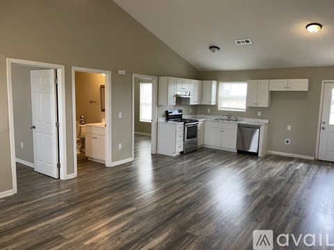 A spacious kitchen with white cabinets and a wooden floor.