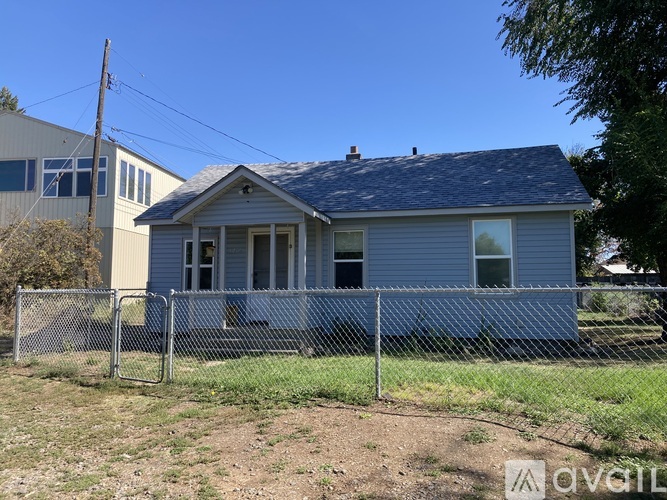A blue house with a grey fence in front of it.