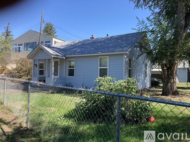 A house with a grey roof and a fence in front of it.
