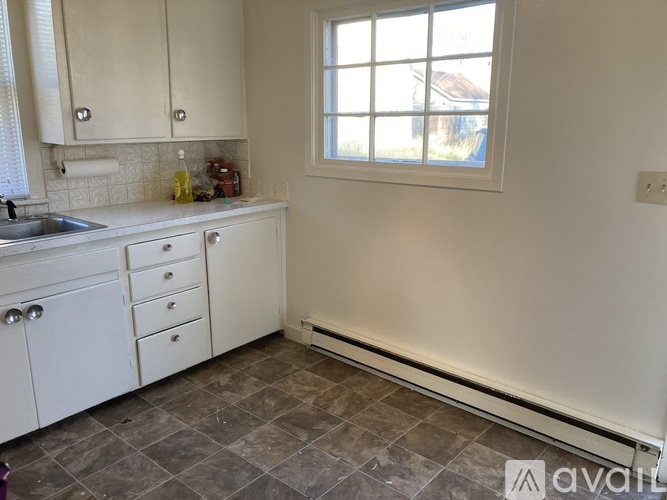A kitchen with white cabinets and a tiled floor.