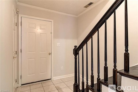 A white door is on the left and a staircase with black railings is on the right.