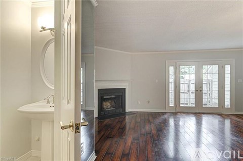 A large, empty room with a fireplace and wooden floors.