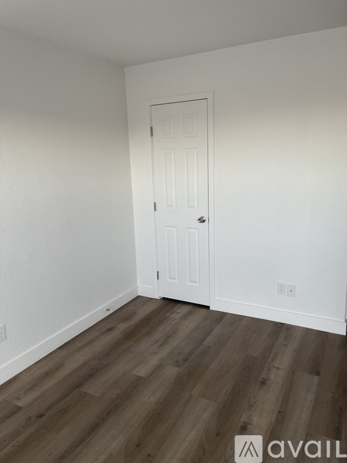 A room with a white door and wooden flooring.