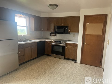 A kitchen with a white refrigerator, black microwave, and black oven.