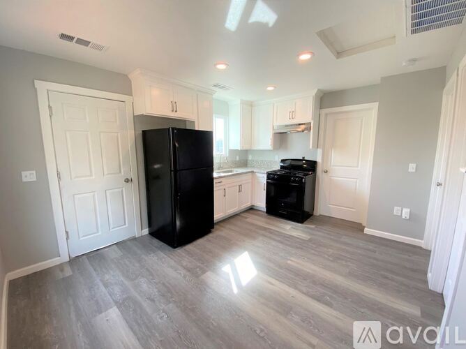 A kitchen with a black fridge and a black stove top oven.