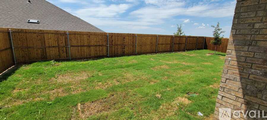 A backyard with a wooden fence and a grassy area.