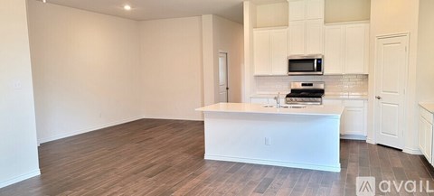 A kitchen with white cabinets and a wooden floor.