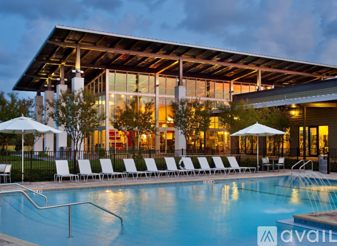 A pool area with lounge chairs and umbrellas in front of a modern building.