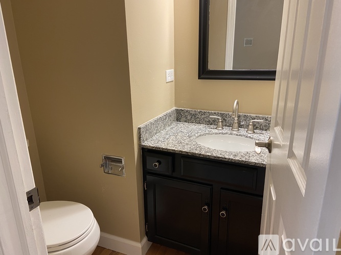 A bathroom with a toilet, sink, and mirror.