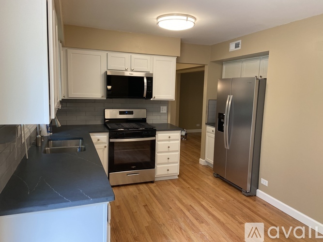 A kitchen with a refrigerator, oven, and sink.