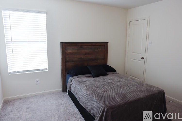 A bedroom with a bed, a window with blinds, and a door.
