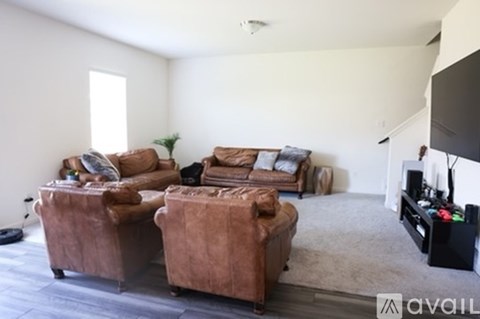 A living room with brown leather furniture and a flat screen TV.