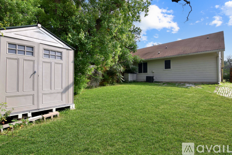 A shed sits in a grassy yard next to a house.