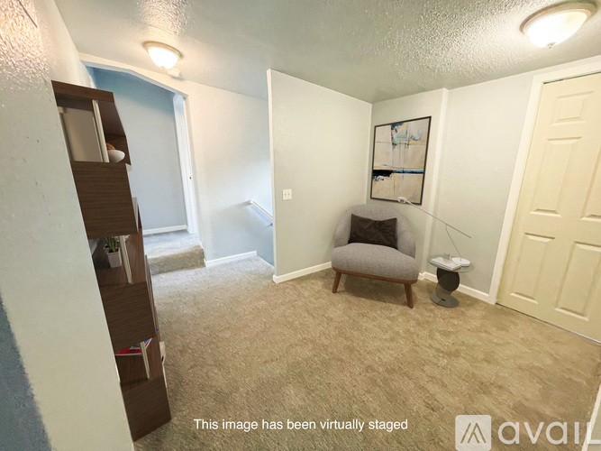 A virtual staged image of a room with a chair, a small table, and a painting on the wall.