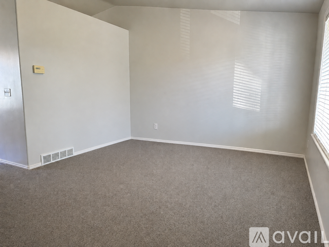 A carpeted room with a window on the right side.