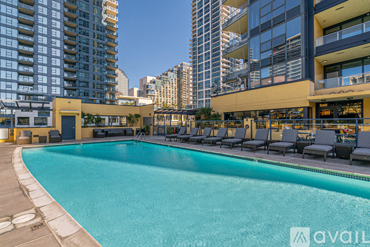 A swimming pool surrounded by lounge chairs and buildings in the background.