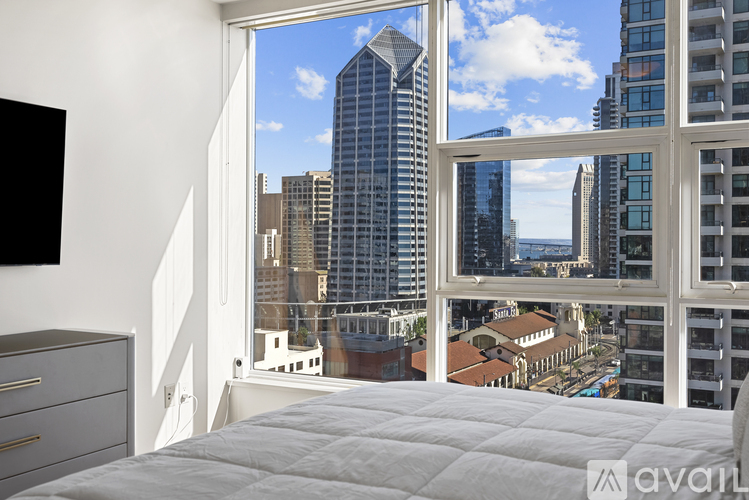 A bedroom with a large window overlooking a cityscape.