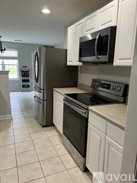 A kitchen with white cabinets and a black microwave.