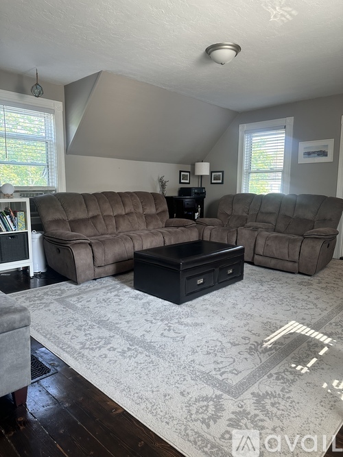 A living room with a brown couch and a rug.