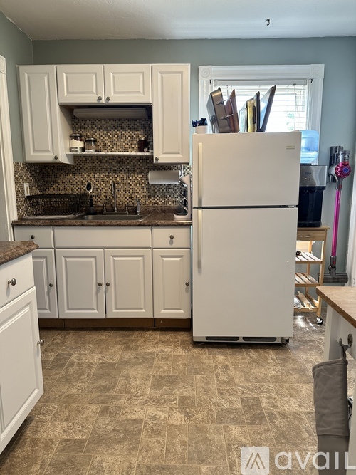 A kitchen with a white refrigerator and cabinets.