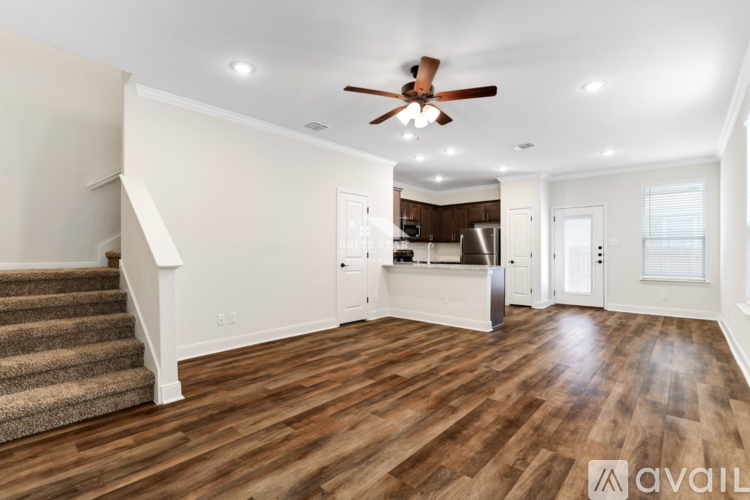 A spacious room with wooden flooring and a ceiling fan.