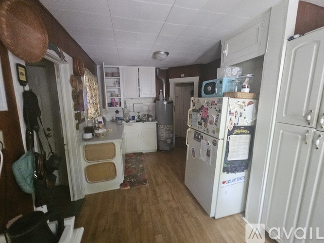 A kitchen with a white fridge and wooden floors.