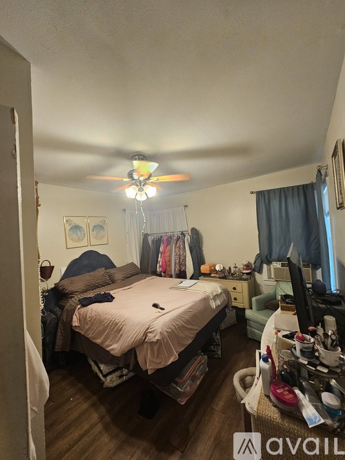 A bedroom with a bed, desk, and cluttered space.