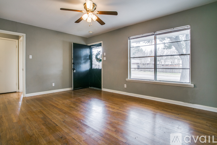 A room with a ceiling fan and a window with a view of trees.