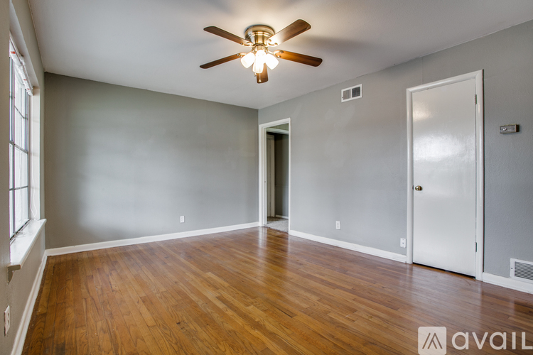 A room with a ceiling fan and wooden floors.