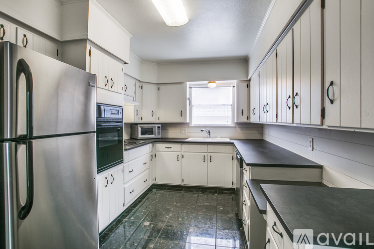 A kitchen with white cabinets and a black counter top.