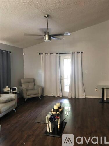 A living room with a fan, a chair, and a table.