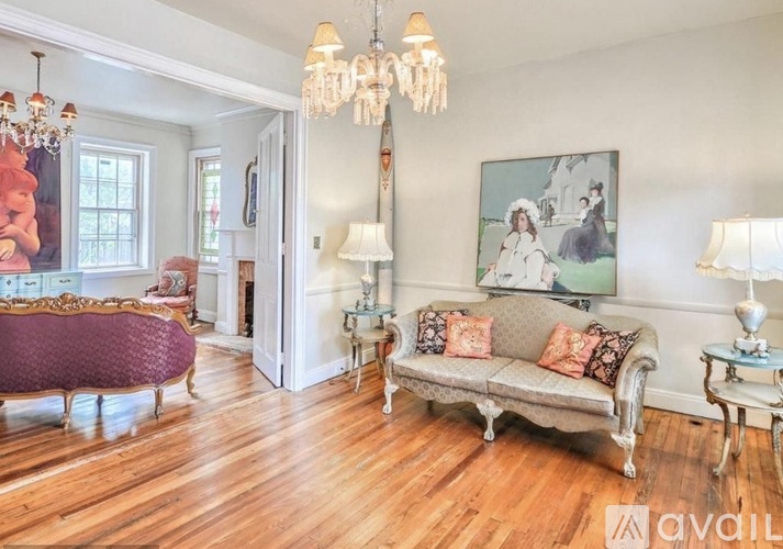 A living room with a purple sofa and a chandelier.
