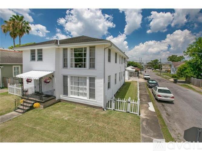 A white house with a porch and a car parked in front.