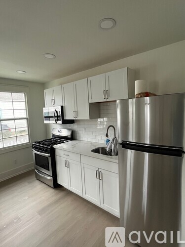 A kitchen with white cabinets and a stainless steel refrigerator.