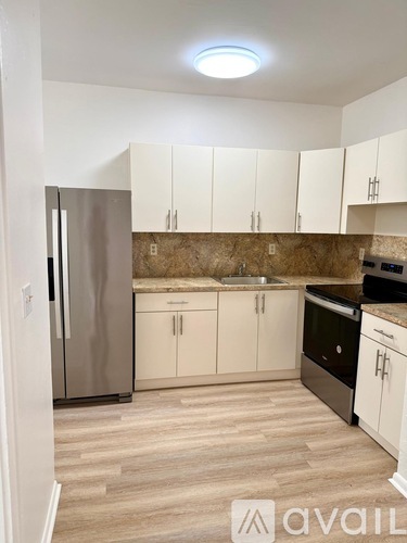 A kitchen with a refrigerator, sink, and cabinets.