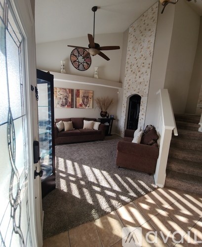 A living room with a brown couch and a fan on the ceiling.