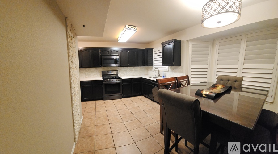 A kitchen with black cabinets and a dining table with chairs.