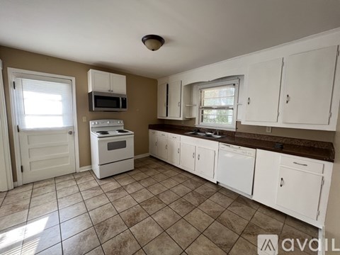 A kitchen with white cabinets and a tiled floor.